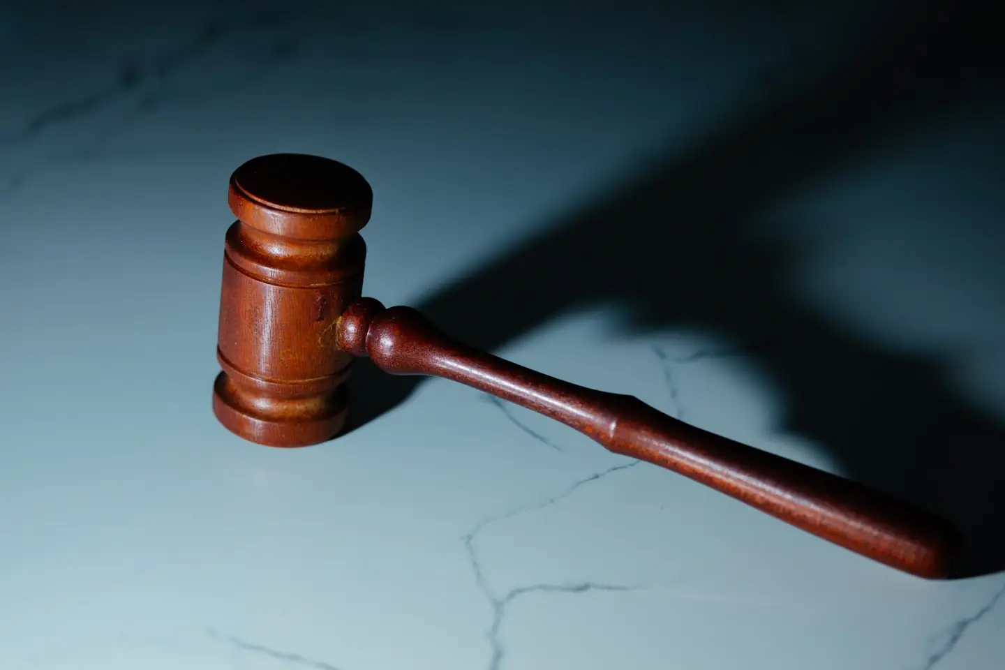 A wooden gavel resting on a white marble surface